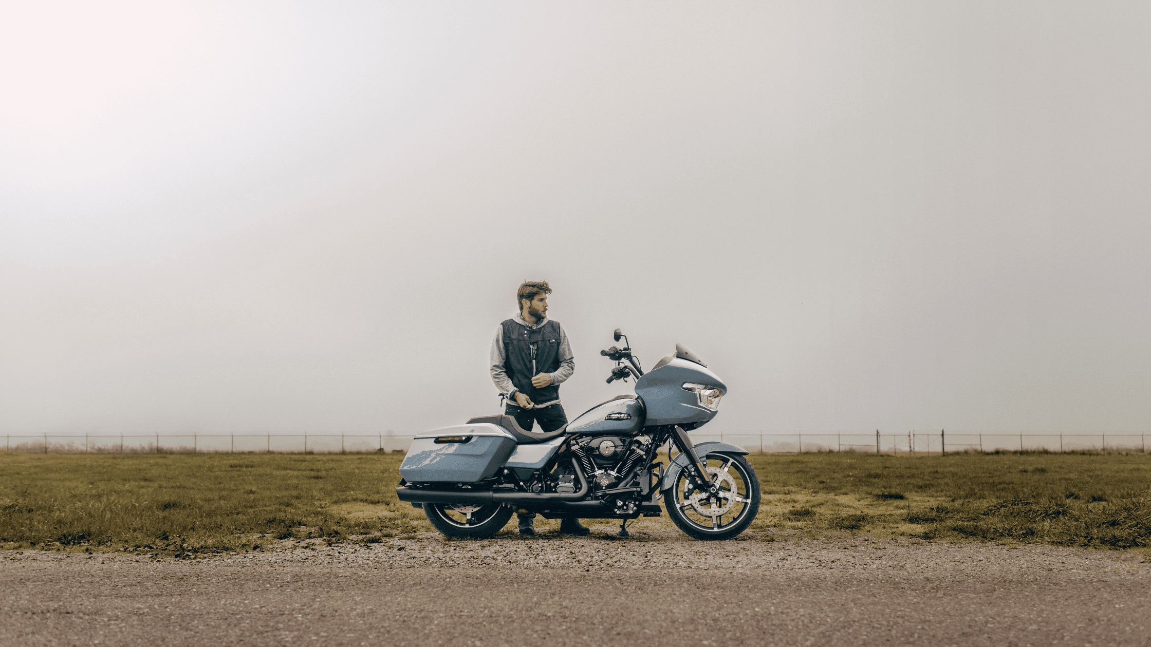 A man enjoys the ride on a 2024 Harley-Davidson® Road Glide® motorcycle, parked on a scenic dirt road.